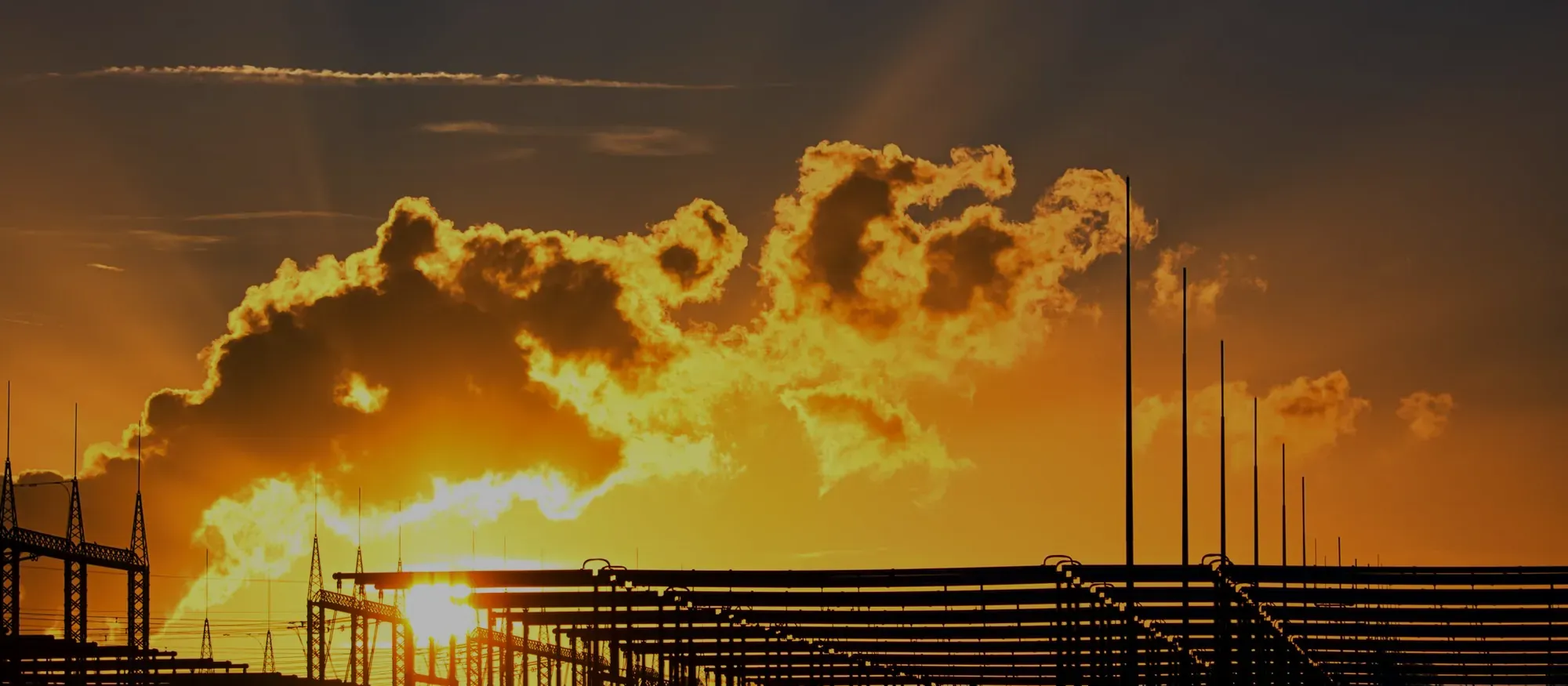 Steel frame of a building under construction, against a glowing sunset sky